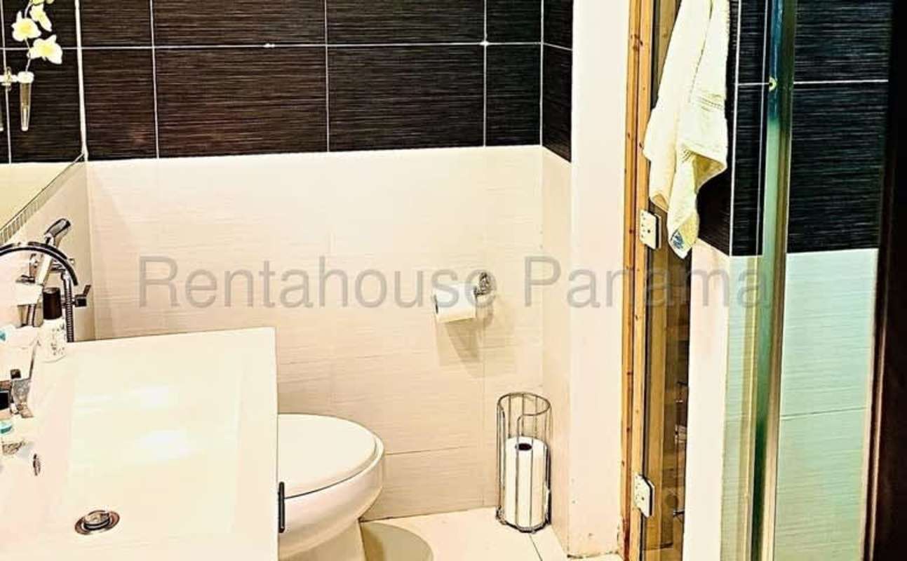 Modern bathroom with white and black tiles, vanity, mirror and glass-enclosed shower at PH San Francisco Tower Panama