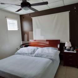 Living room with yellow sofas, tile floor, ceiling fan and stone accent wall in Villas de Montelimar Panama