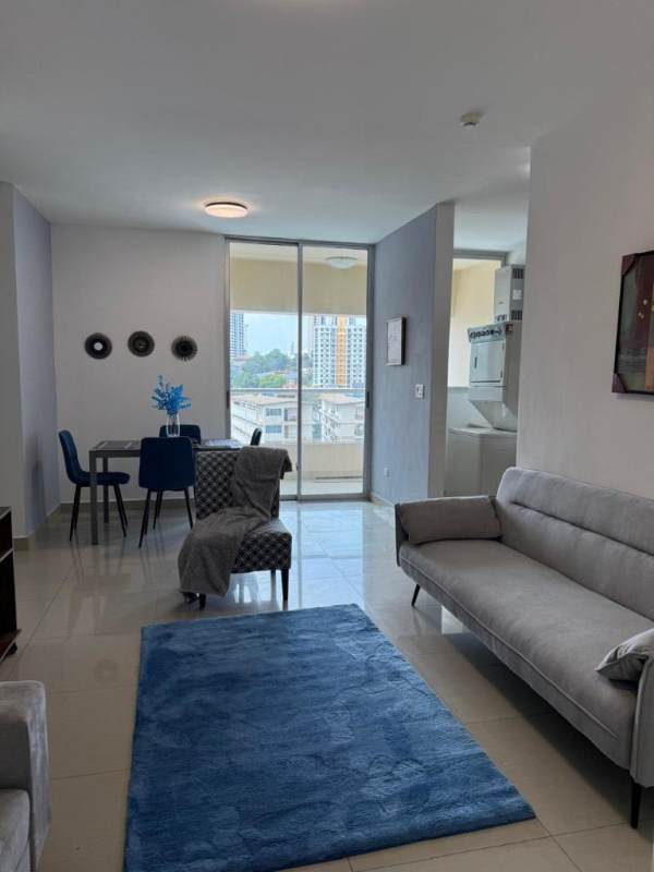 Living and dining area with blue rug, gray sofa, washer-dryer, balcony view in PH San Francisco Bay Panama