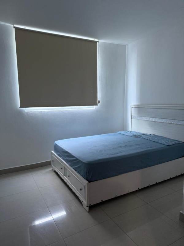 Minimalist bedroom with tile floor, blackout shade, blue bedding overlooking Panama skyline