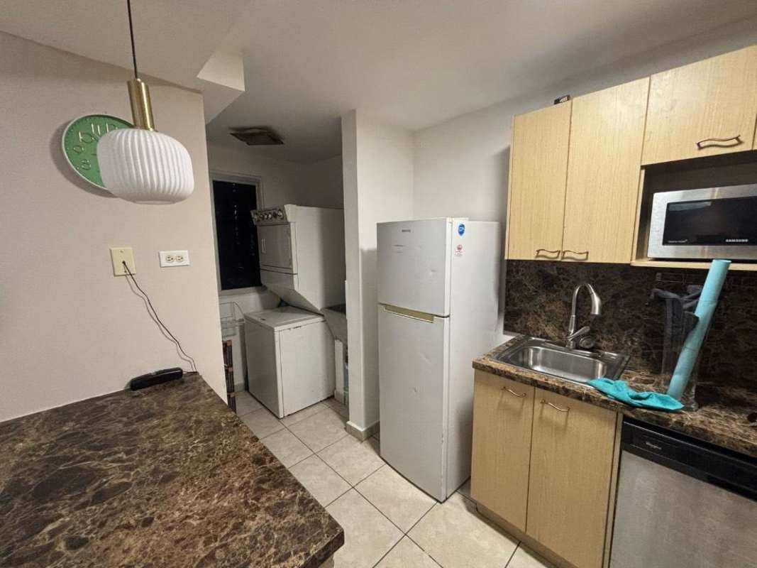 Compact modern kitchen with washer dryer tower, microwave and marble counters in PH Sunshine Carrasquilla Panama rental