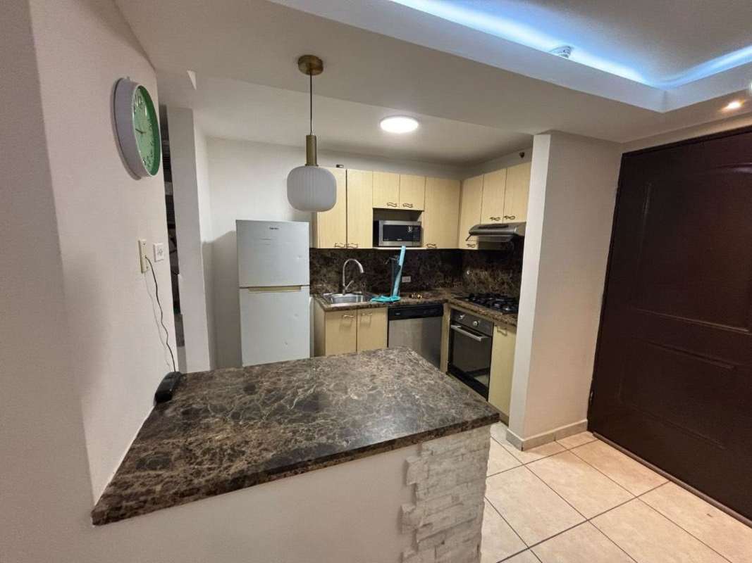 Modern kitchen with marble countertops, beige cabinets, refrigerator and stainless appliances in PH Sunshine rented apartment Panama