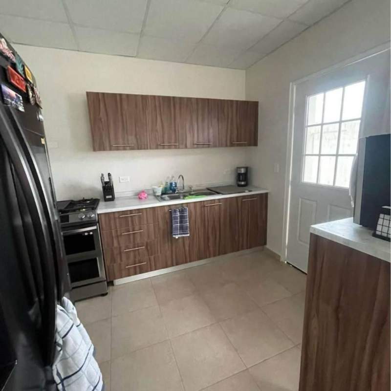 Kitchen with wood cabinets, tile floor, windowed door rental house Pacora Panama