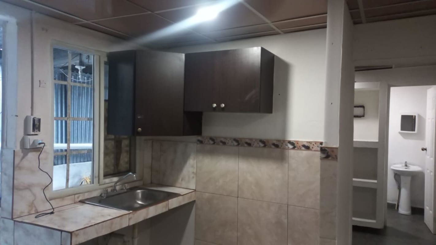 Basic kitchen setup with window, cabinets and tile counters in Pedregal apartment