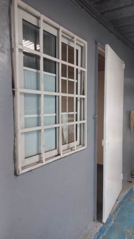 Apartment building exterior with window grille and open door in Villalobos Pedregal