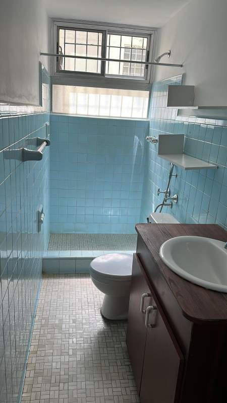 Bathroom with blue wall tiles, walk-in shower, wooden vanity at PH Via Argentina Panama