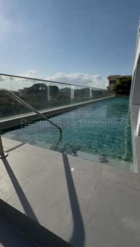 Infinity pool on rooftop with glass enclosure overlooking Panama skyline