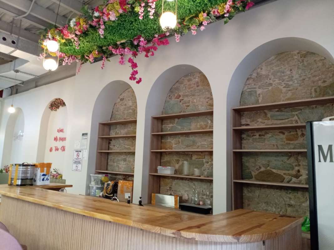 Rustic wooden cafe counter with stone accents and hanging floral arrangements in commercial space Casco Viejo