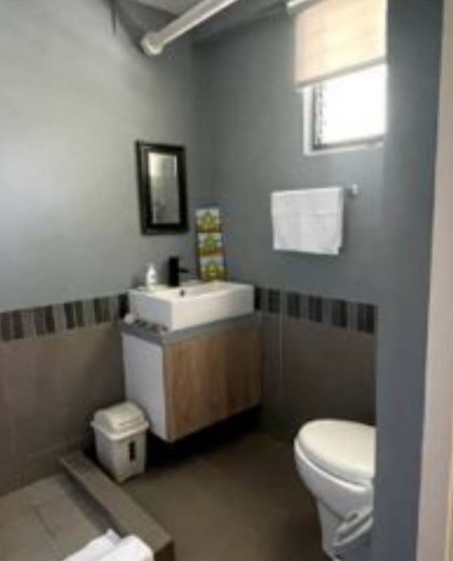 Minimalist gray bathroom with modern vanity sink, wall mirror, and shower PH Albrook Residences Panama City