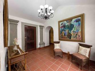 Mediterranean-style entry with terra cotta tiles, chandelier, art and arched doorway in Buenaventura