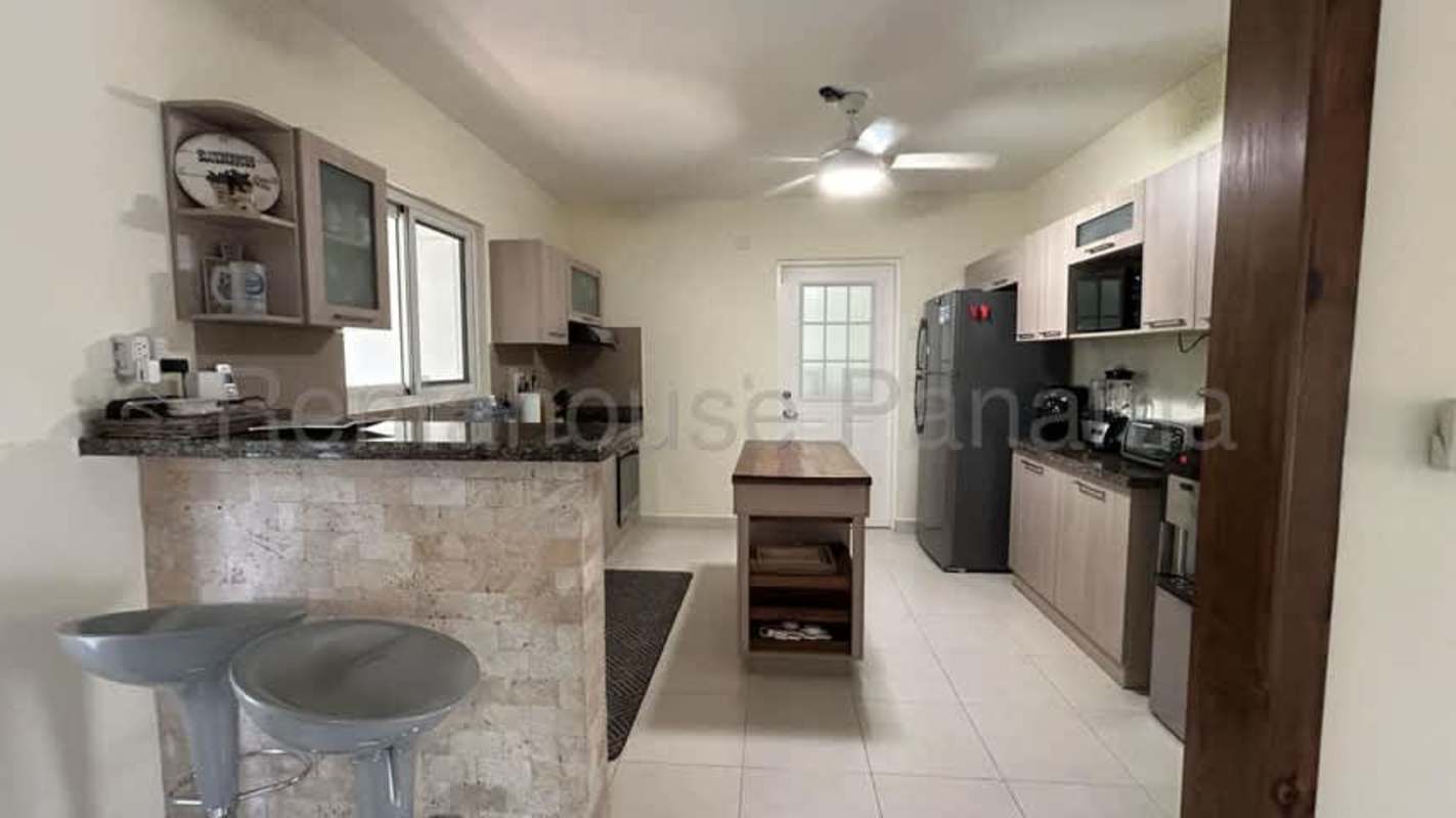 Dining room with glass table, pendant lighting, exposed beams in duplex Panama