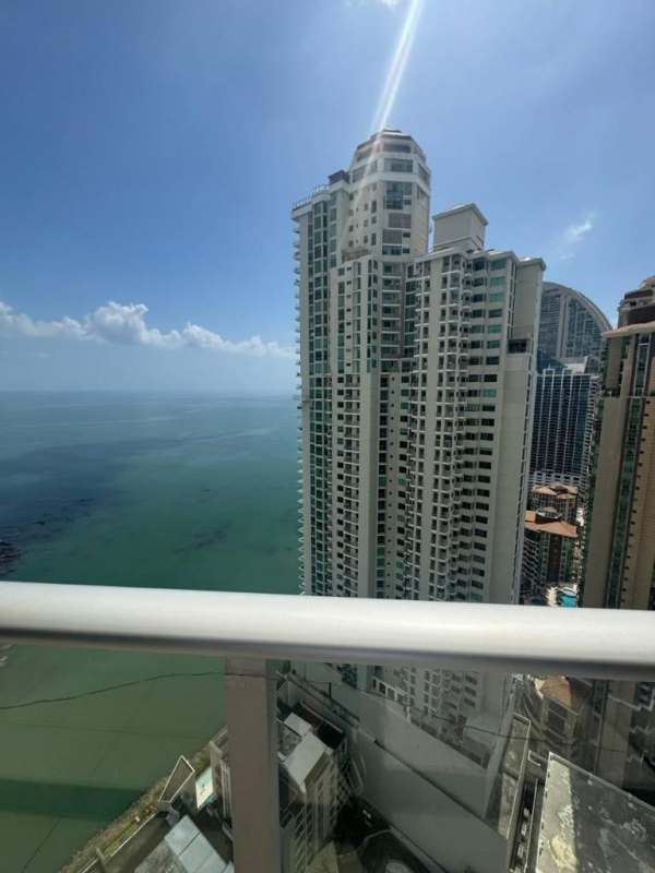 Modern furnished living room with floor-to-ceiling windows and balcony access in Punta Pacifica Panama