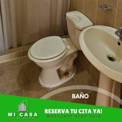 Compact bathroom with ceramic tiles, pedestal sink, toilet, and shower curtain in affordable house Penonomé Panama