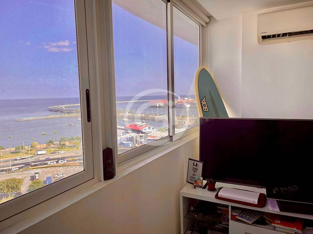 Living space with TV, surfboard decor, large windows Panama Bay view at PH Bay View Panama