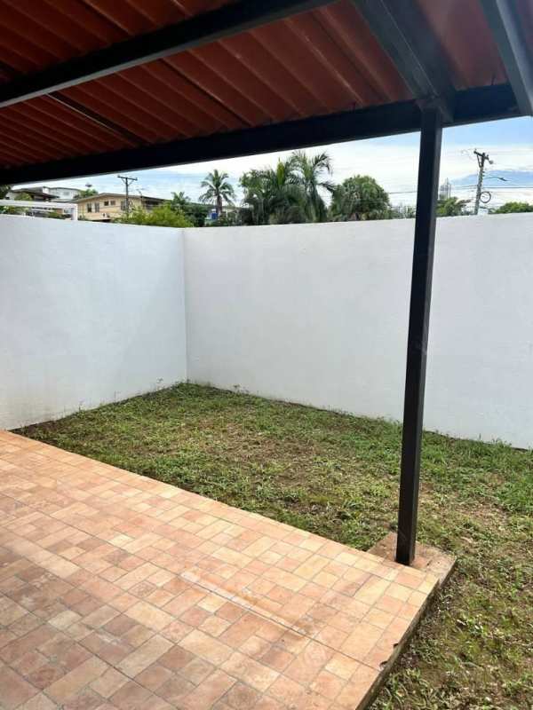Small grassy backyard with covered tiled patio inside white perimeter wall La Gloria Betania