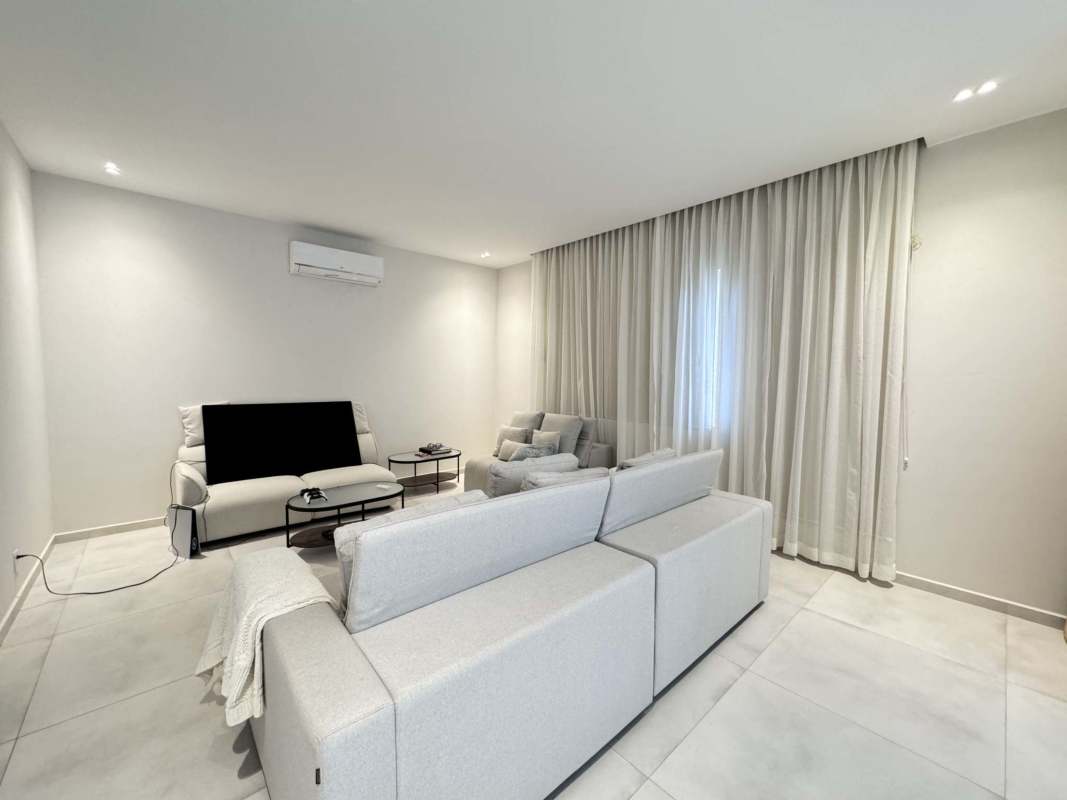 Spacious open-plan living area with large windows, neutral décor, garden view in Santa María