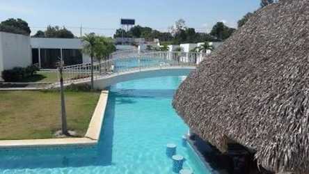 Outdoor resort setting with pool, palapa roof club and tropical landscape Village at The Pool Rio Hato Panama