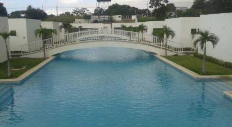 Expansive outdoor pool with white bridge and palm trees in gated Village at The Pool Rio Hato Panama