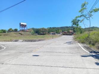 Rural paved road passing near water tank, open countryside and scattered homes near David Chiriquí Panama