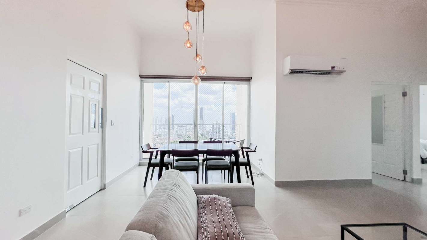 Bright open-plan living dining area with balcony, ceiling fans, large windows at PH Costa del Mar Panama
