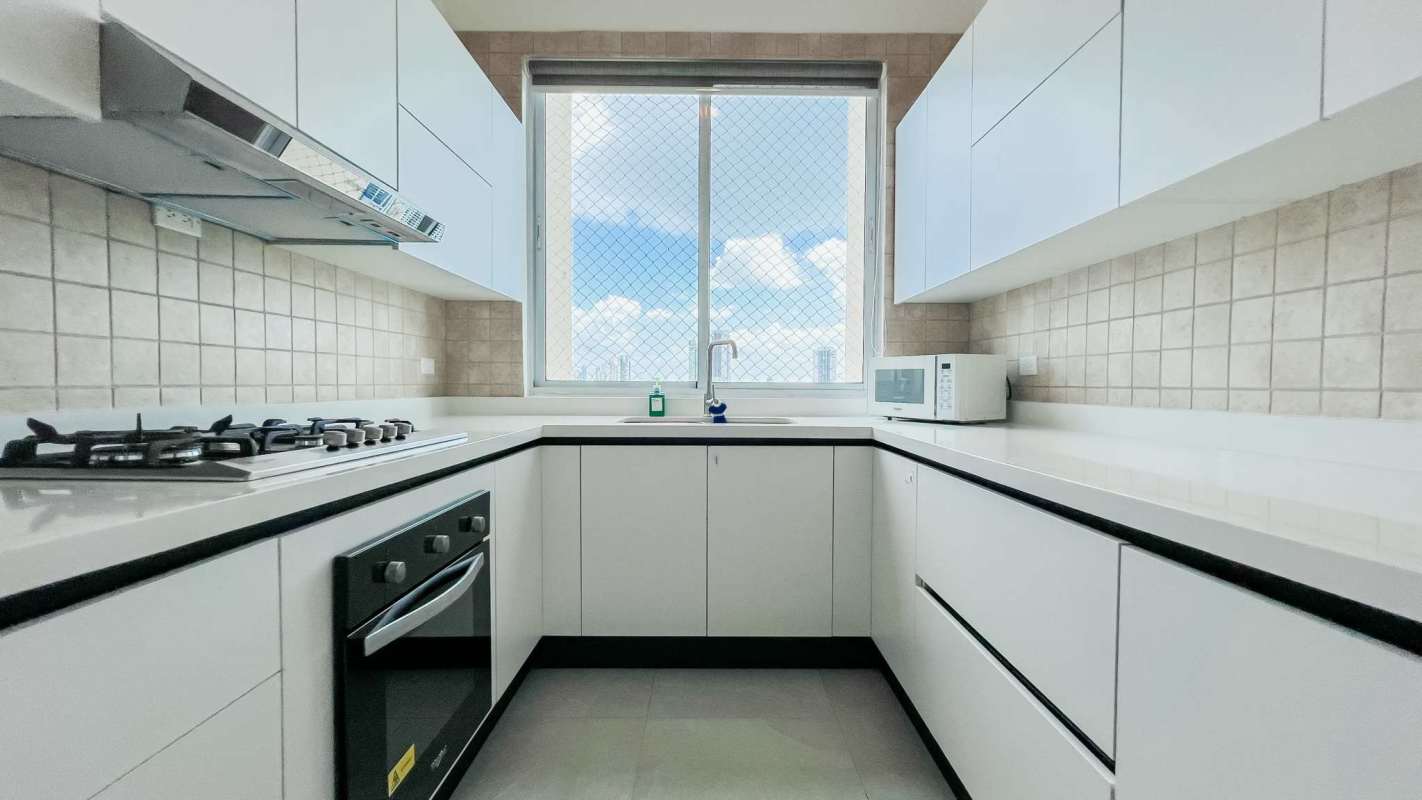Minimalist kitchen with built-in microwave, gas stove, large window city view PH Costa del Mar Panama City