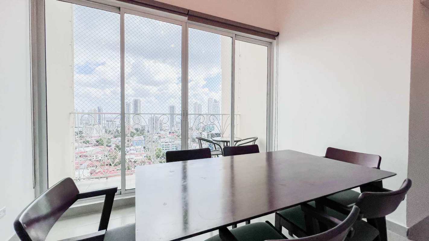 Dining room with large sliding doors opening to balcony with skyline view PH Costa del Mar Panama City
