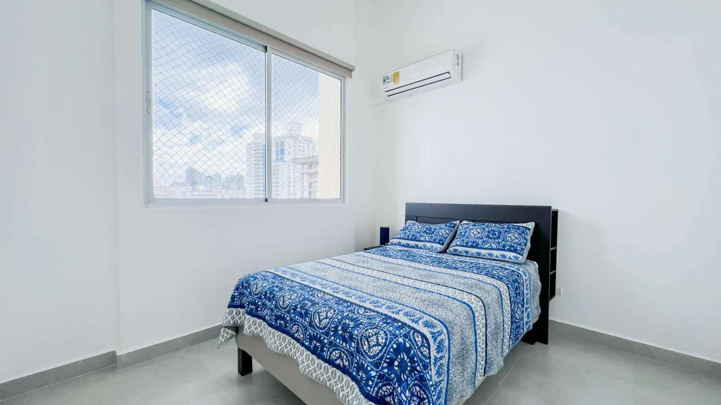 Bright bedroom with blue decor, large window city view and air conditioner in PH Costa del Mar Panama