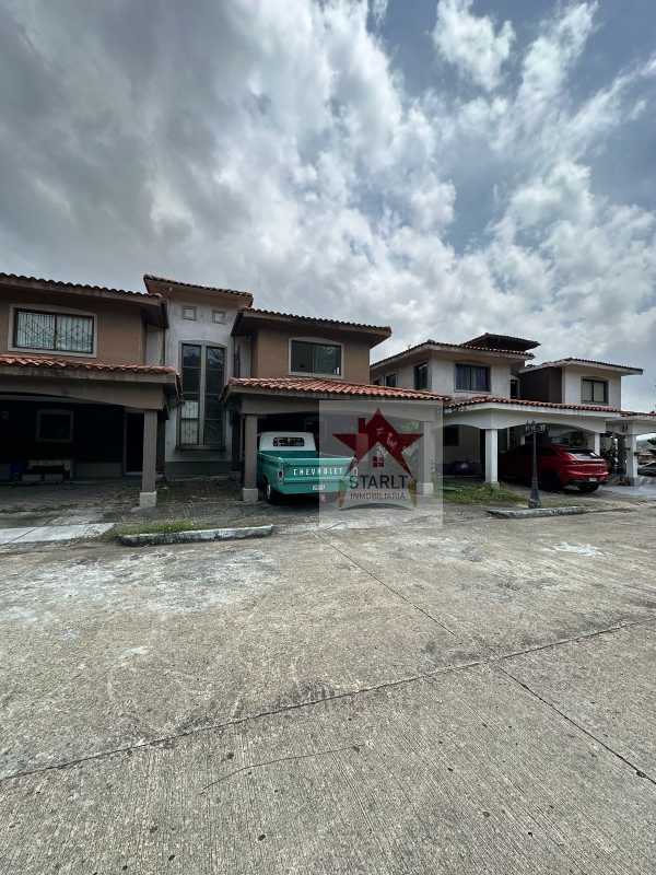 Exterior view of two-story house with red tile roof, covered parking and front driveway PH Green Village Panama