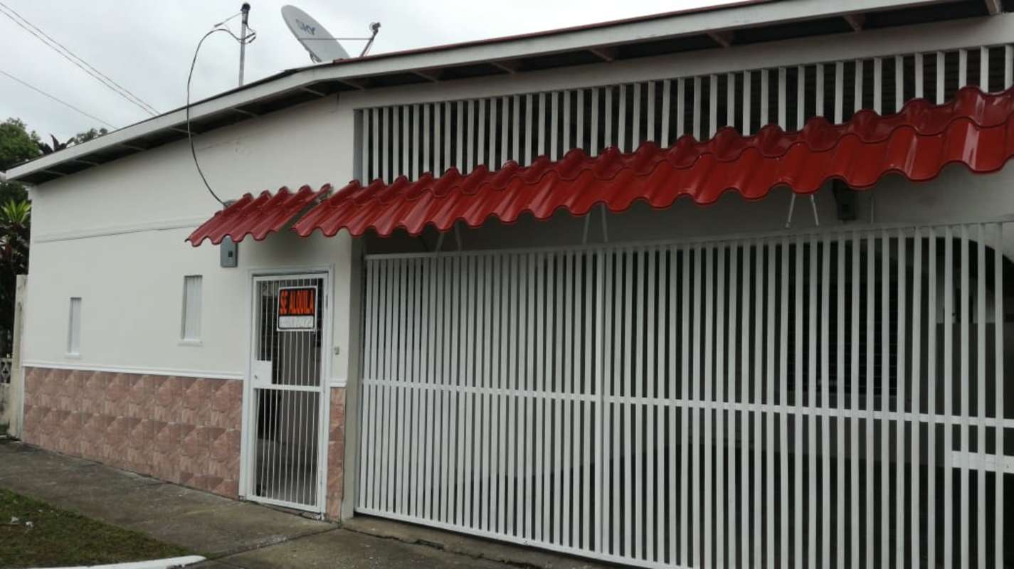 Front view with red awning, metal gate house in Colinas Dorasol Panama for sale