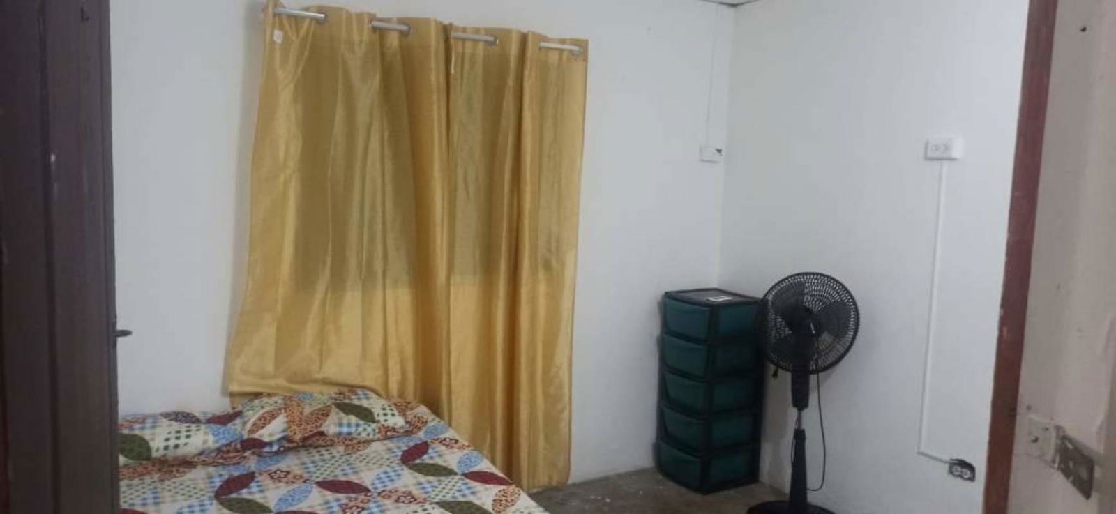 Spacious furnished rental bedroom with bed, gold curtain, standing fan and storage in Villa Lucre Panama