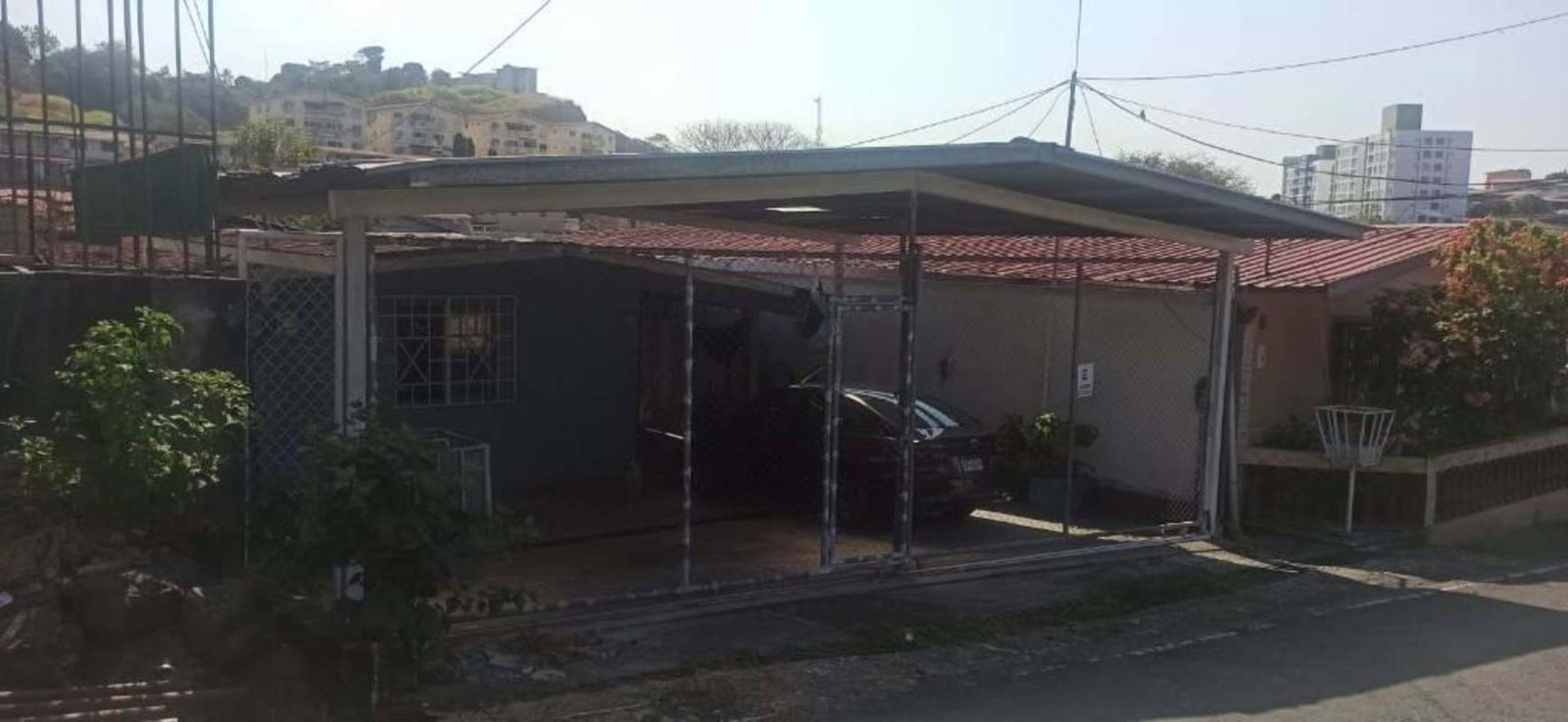 Covered carport with metal security gate, hammock and garden plants Villa Lucre residential