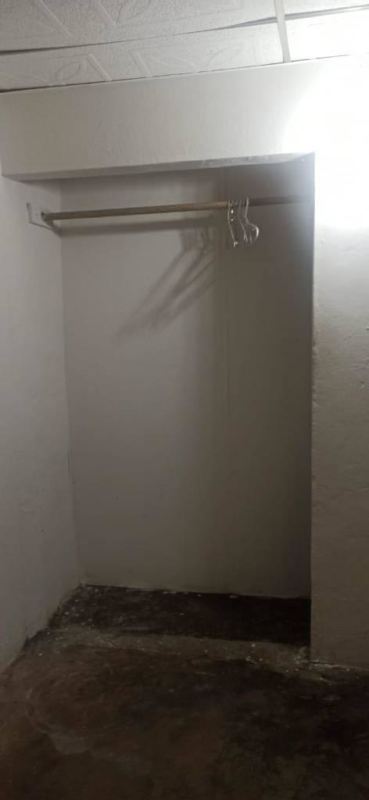 Simple closet space with hanging rod and plastic hangers minimalist Villa Lucre room rental