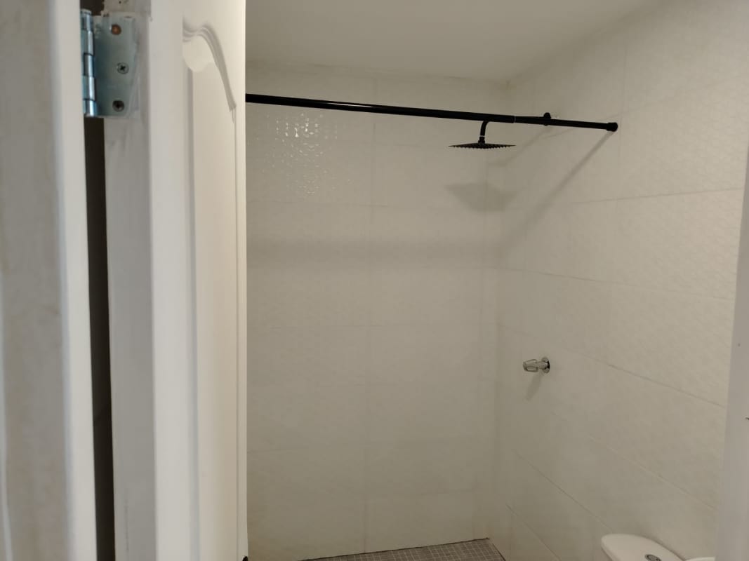 Minimalist white bathroom with walk-in shower in PH Aurora apartment El Cangrejo Panama