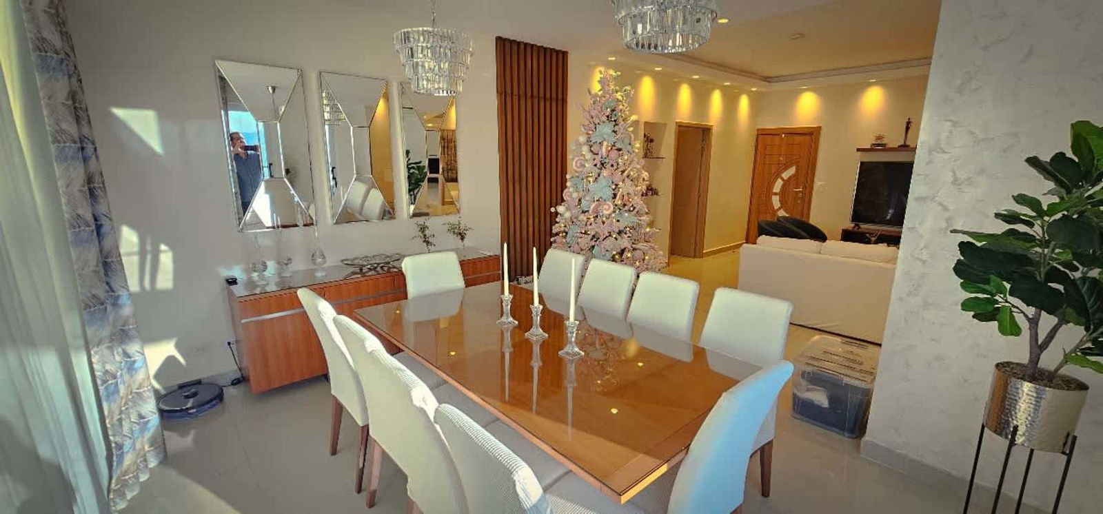 Contemporary dining and living space with glass dining table, chandeliers, and festive decor in PH South Coast Panama