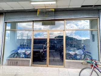 Commercial storefront with large reflective glass windows, metal doors and motorcycles visible inside