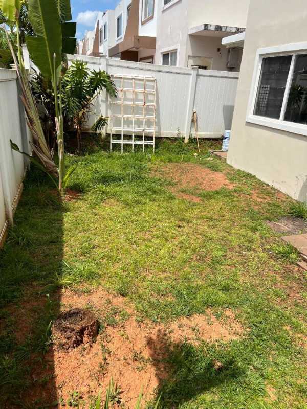 Townhouse backyard garden with green lawn, white fence and tropical plants in PH Everest Panama City