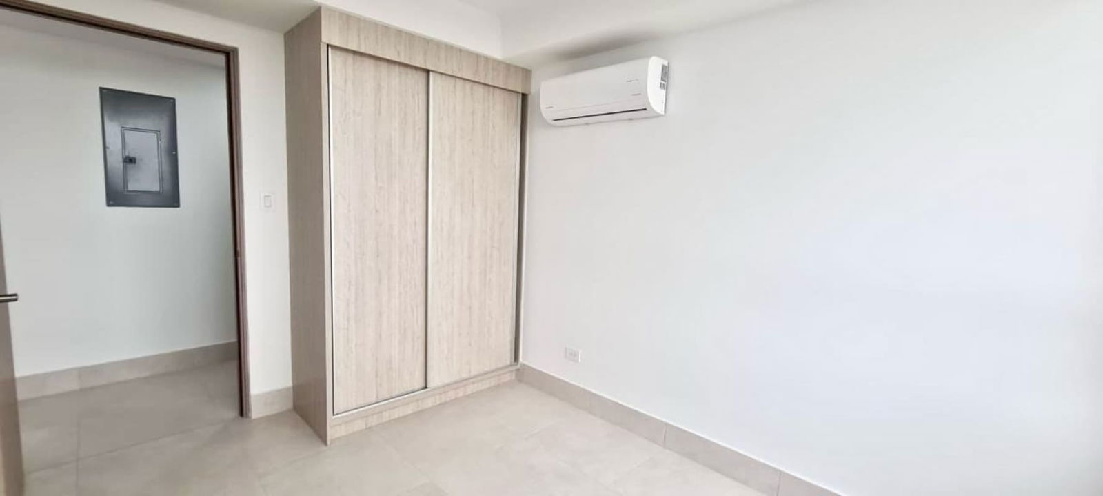 Bedroom interior with built-in wood wardrobe, neutral colors at Greenwood Towers Panama