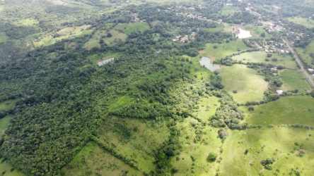 Aerial of large farm land with grass, forest patches, buildings Cerro Cama Panama