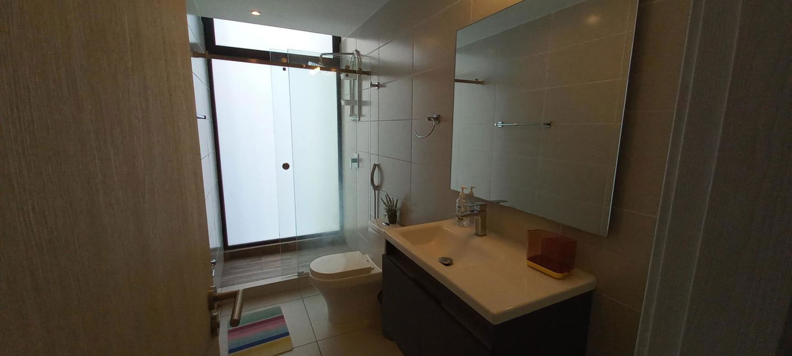 Sleek bathroom with glass enclosed shower in Coco del Mar Panama apartment for rent
