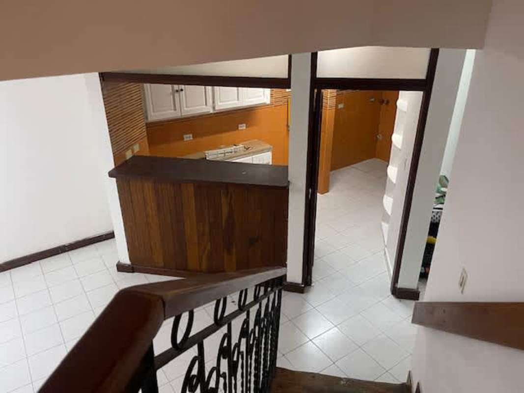 Kitchen with breakfast bar, white cabinets, wooden accents seen from staircase in Obarrio townhouse Panama