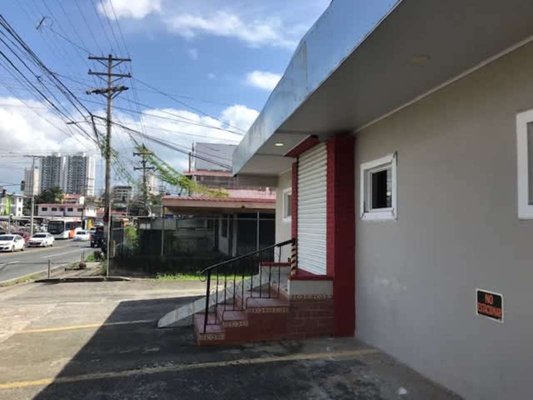 Urban street view with building entrance, storefront shutter, and sidewalk at Villa Cáceres Panama City