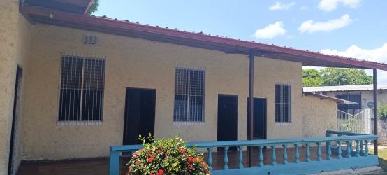 Beige one-story home with blue porch railing red roof near beach in Panama great for rentals