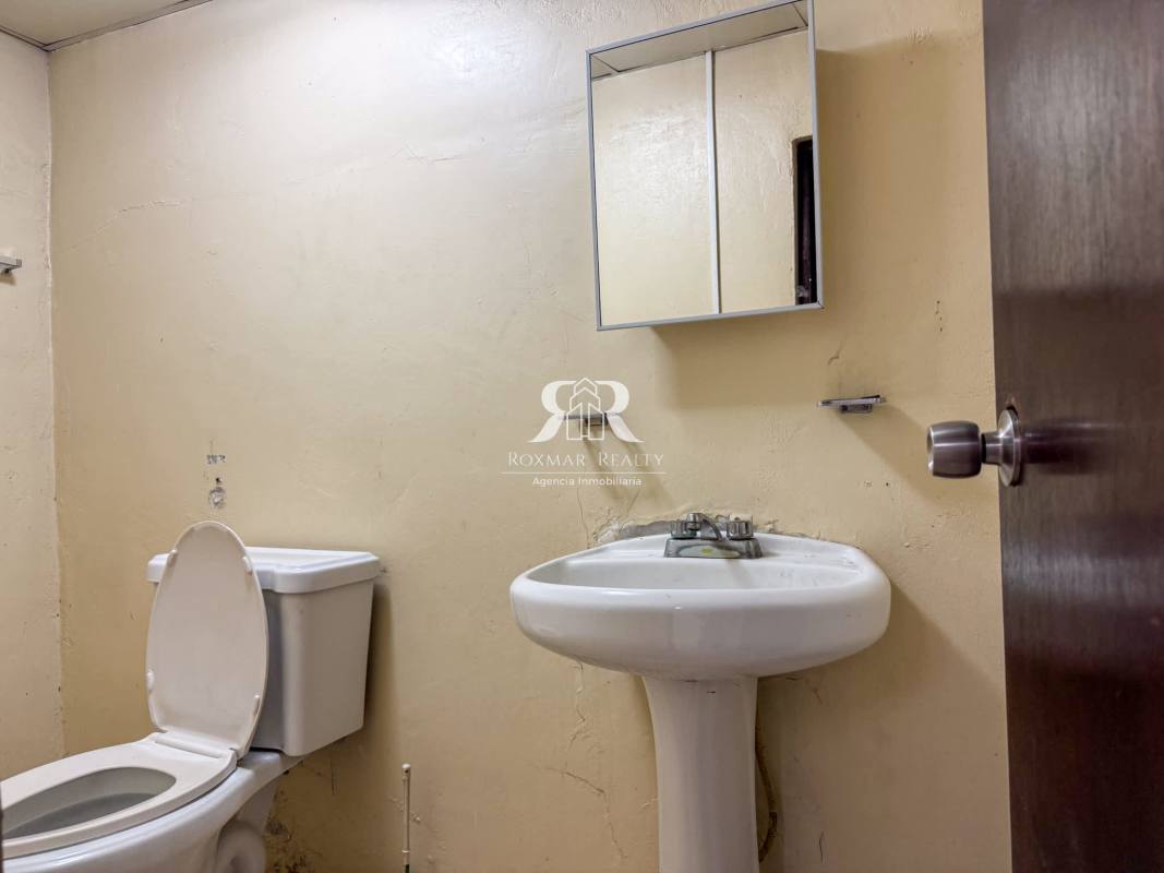 Basic utilitarian bathroom with sink toilet beige walls inside commercial warehouse Panama