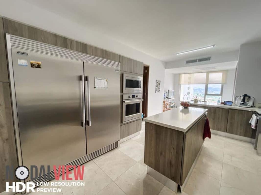 Spacious kitchen featuring center island, stainless appliances, city skyline window views in luxury golf condo