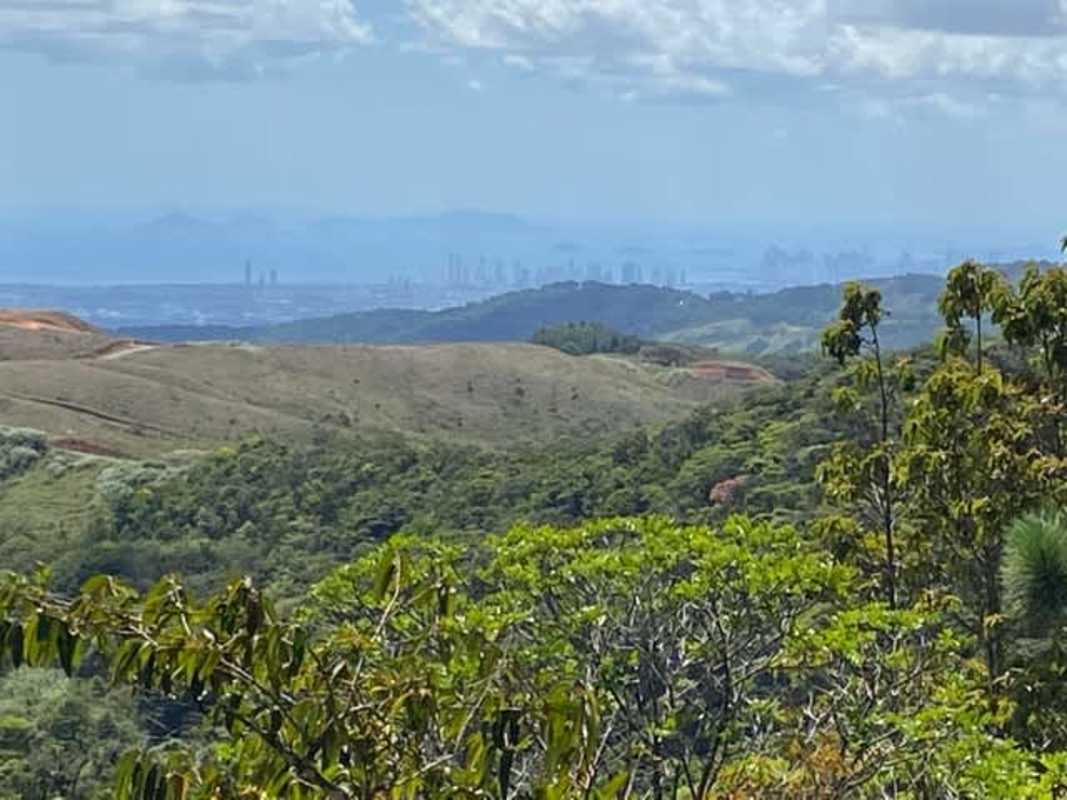 Expansive view of forested mountains and valleys with Panama City skyline from Cerro Azul land