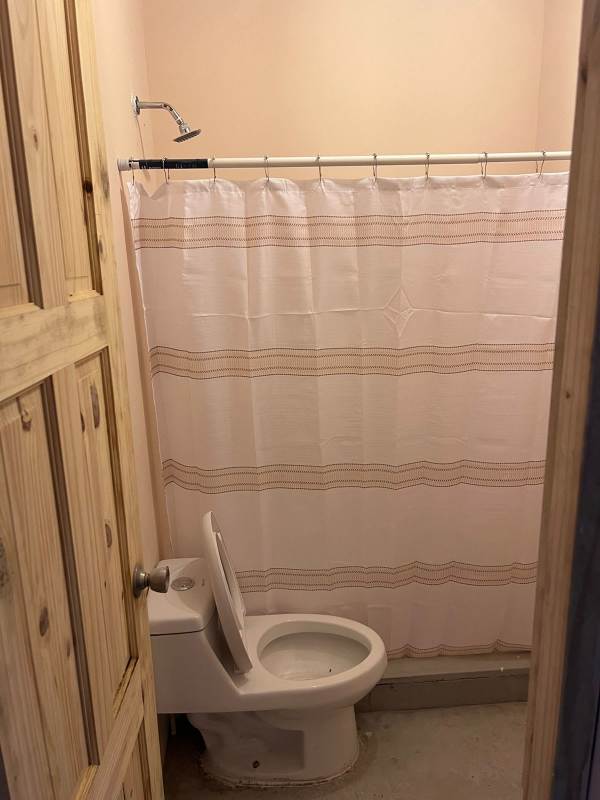 Small bathroom with toilet shower curtain and wooden door in rental Paraiso Panama City