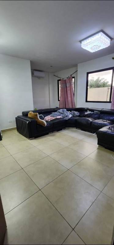 Large sunny living room with tiled floor, big windows, and black sofa inside house at PH Olympus & PH MontBlanc Brisas del Golf Panama City