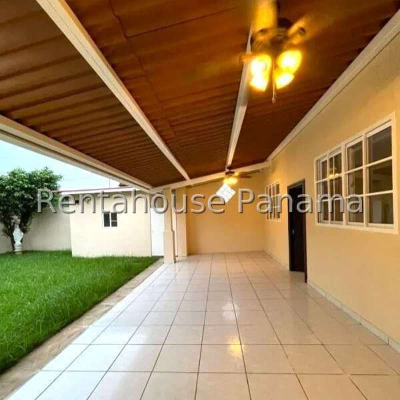 Covered backyard patio with tiled floor, fans, adjacent garden in Condado del Rey Panama