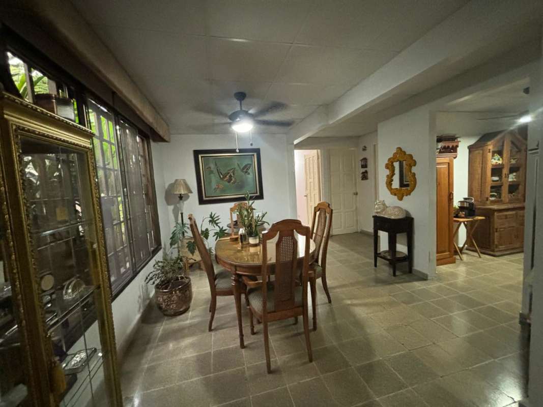 Dining room with large window, glass cabinet, wooden furniture, ceiling fan