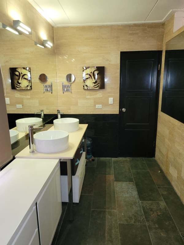 Modern living area with sofa, swivel chair, TV and Buddha art in PH Via Argentina Suites